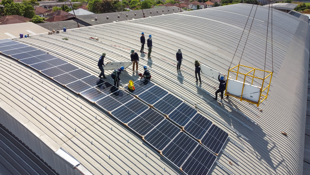 a group of people standing on a roof with solar panels - renewable natural gas